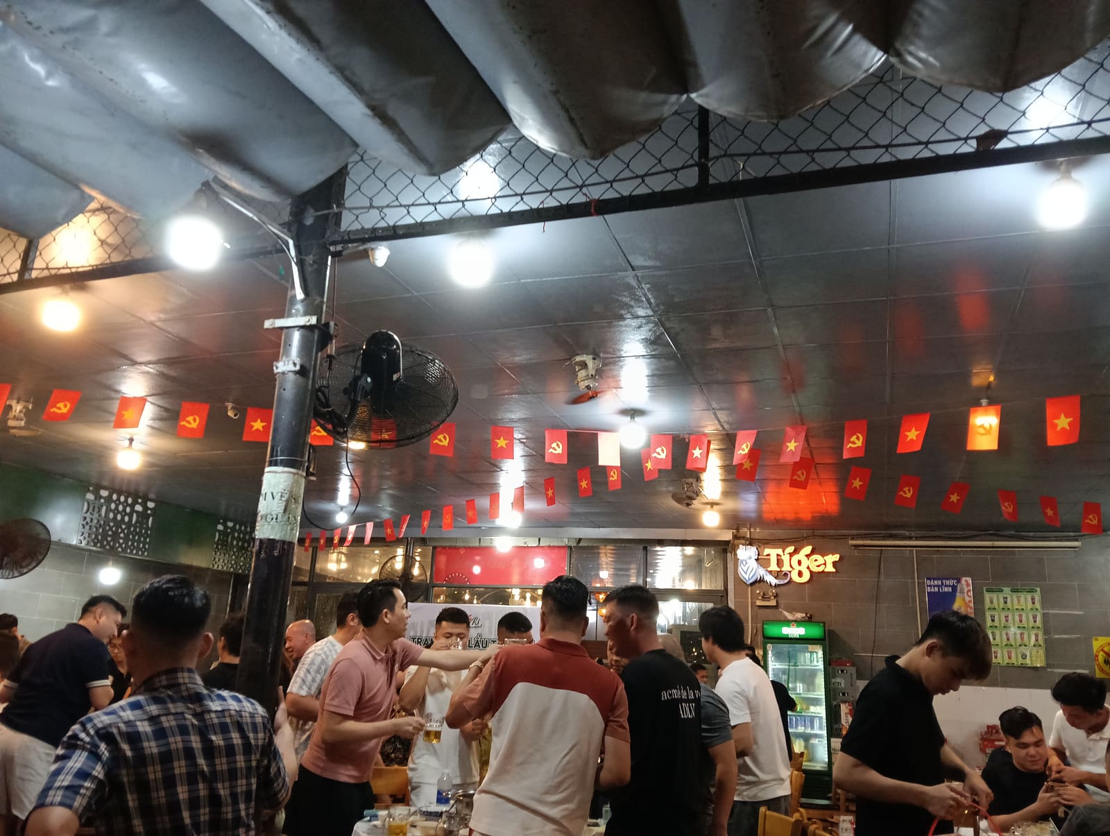 胡志明市 Lẩu Tôm 5 Ri 5 海鮮店現場，越南國旗、Tiger 啤酒招牌、當地人聚會的熱炒店氛圍