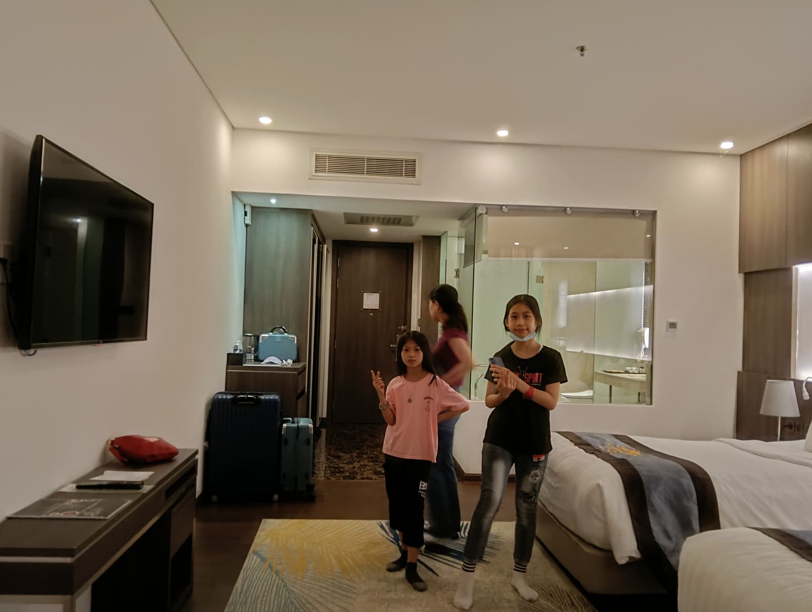 The Mira Central Park Hotel 家庭房內裝，兩個女兒在房間中間擺姿勢，旁邊有兩個行李箱